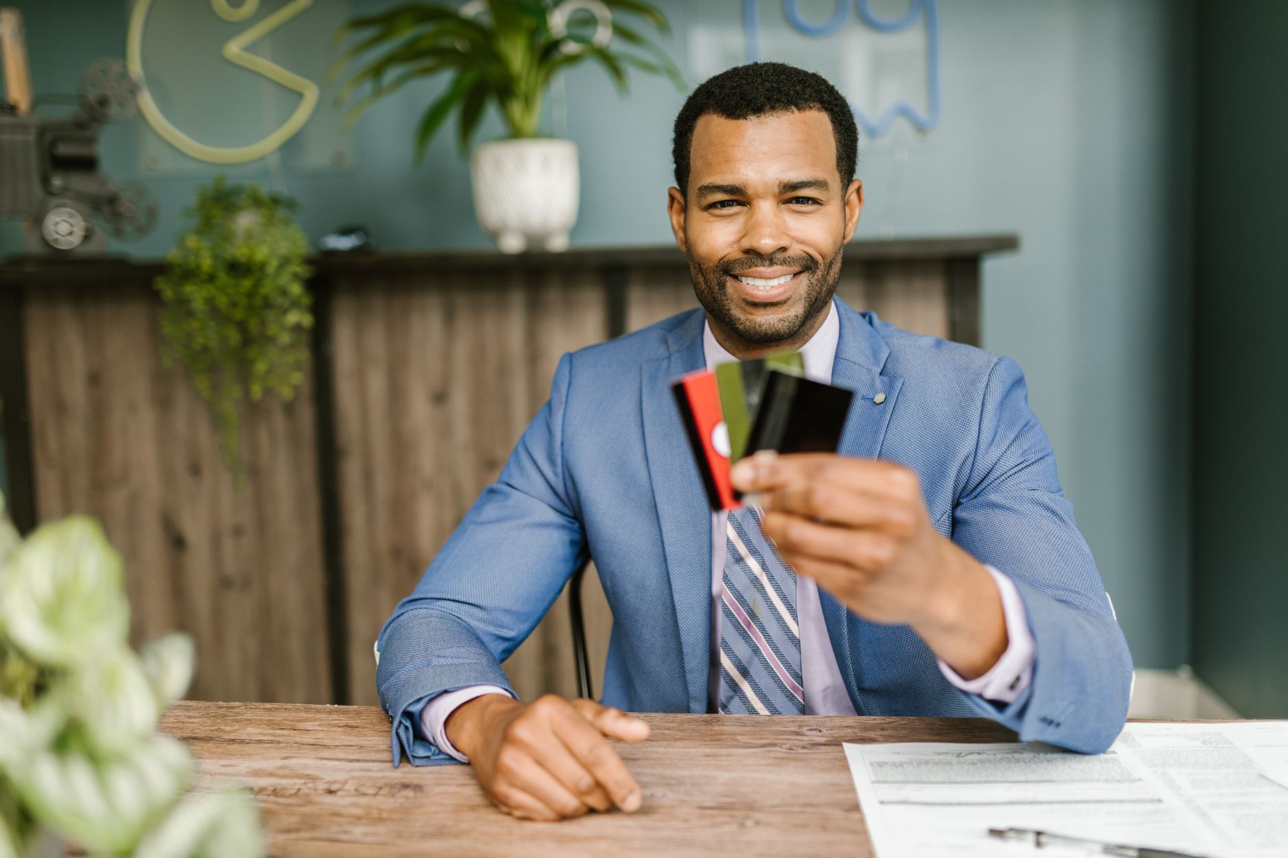A man in a blazer holding out a fan of credit cards